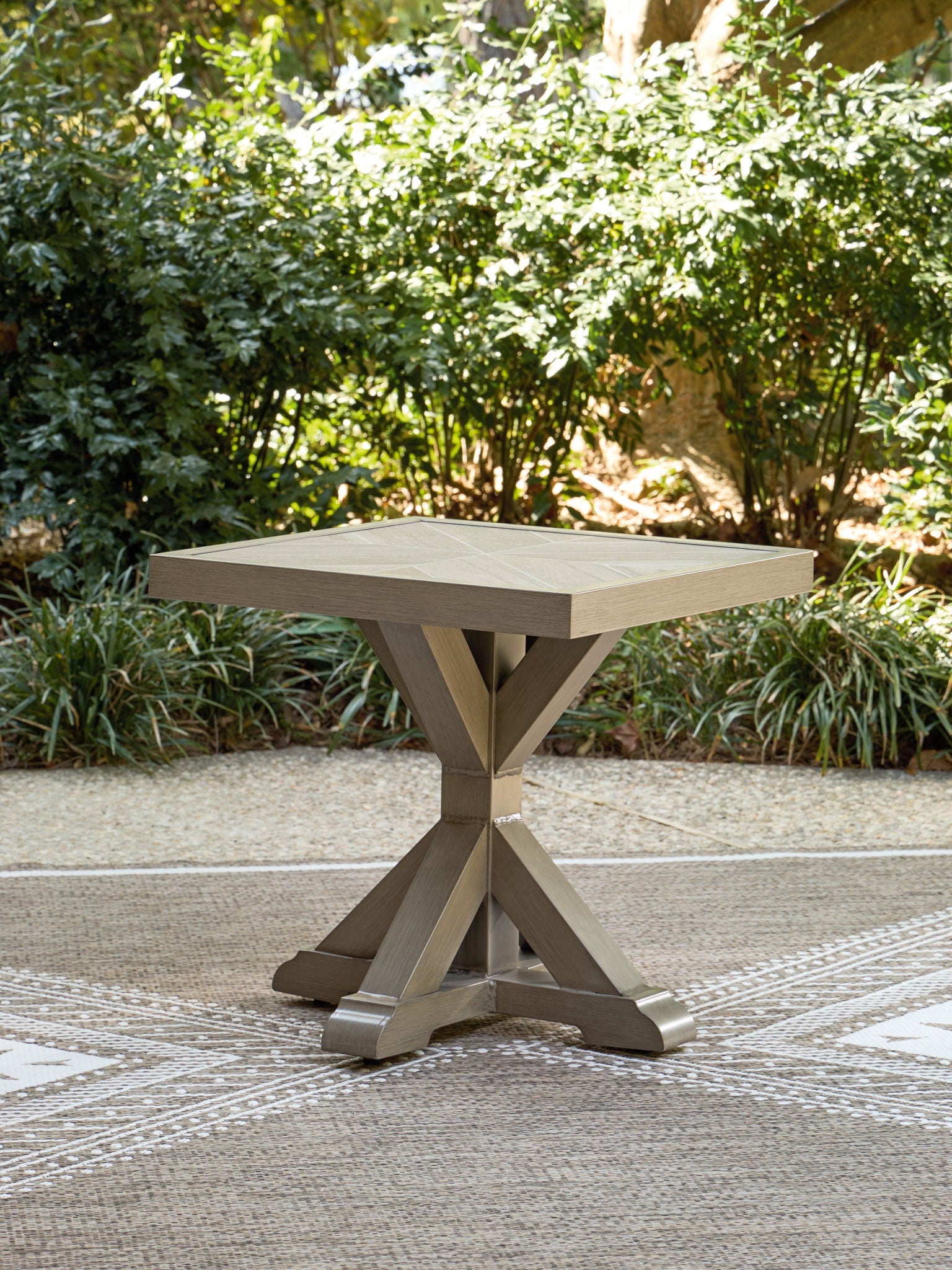 Beige square end table outdoors with wide square top and X-style pedestal legs
