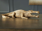 Antique gold crocodile sculpture lying on side, textured body and teeth