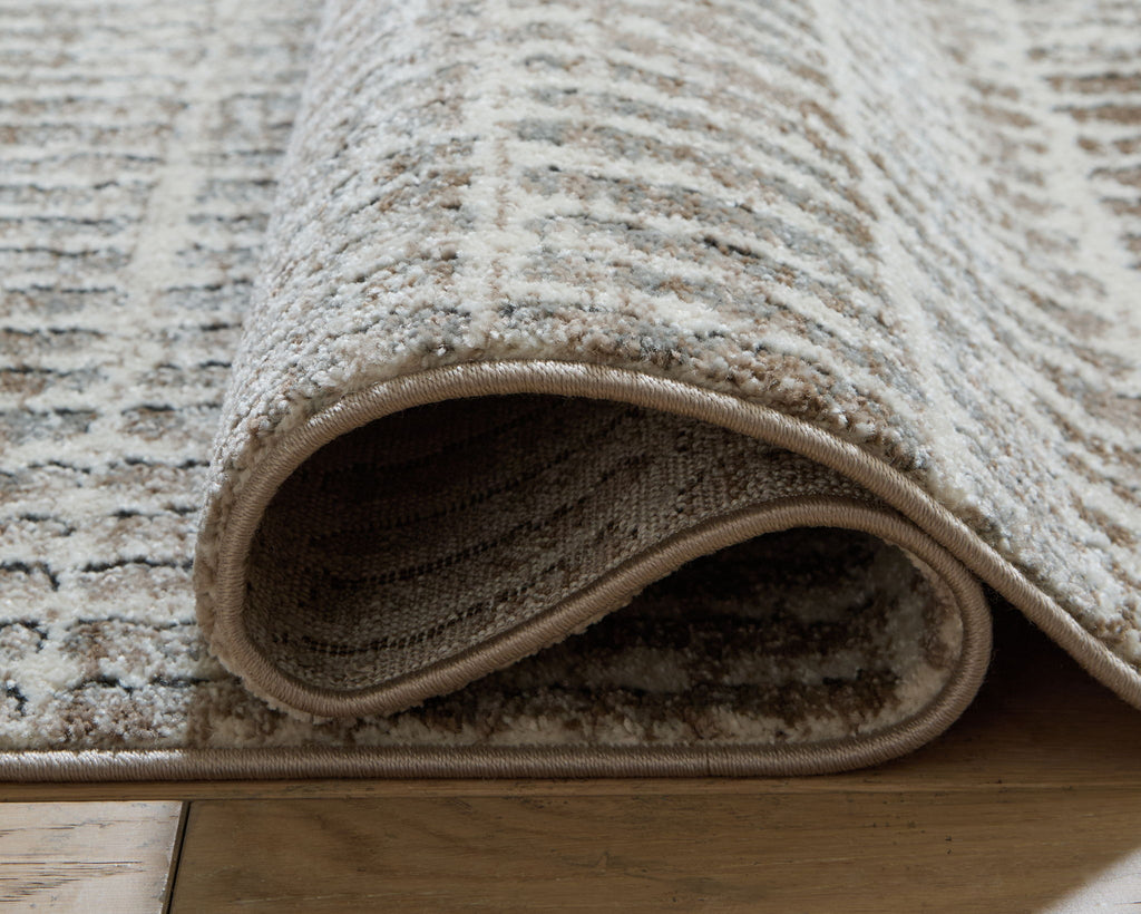Gray area rug edge with stitched binding and low-profile weave