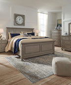 Gray panel bed centered in room with cream quilt, navy cover, and patterned pillows