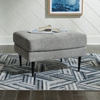 Upholstered ottoman with rounded cushion top and tapered black legs