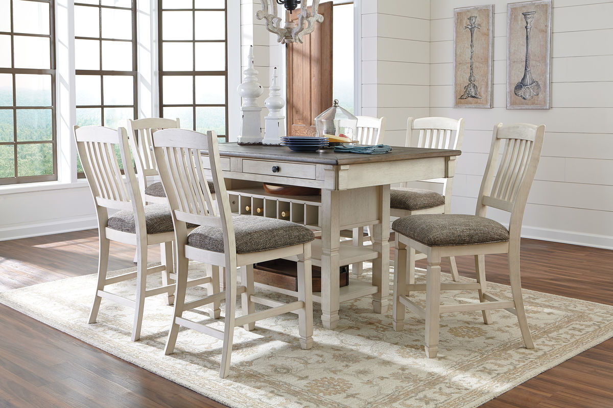 Beige dining table set with rectangular table, cushioned stools, and white slat chairs