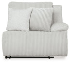 Light gray ribbed power recliner with two accent pillows and rounded armrests