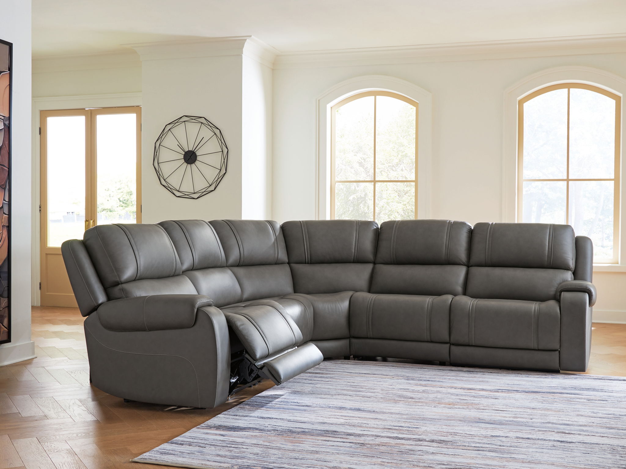 Dark gray power reclining sectional with chaise end, padded arms, and visible recliner mechanism