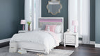 White panel bed with paneled headboard, footboard, and dressed bedding