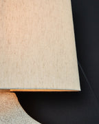 Paper table lamp close-up: square fabric shade edge over textured antique beige base