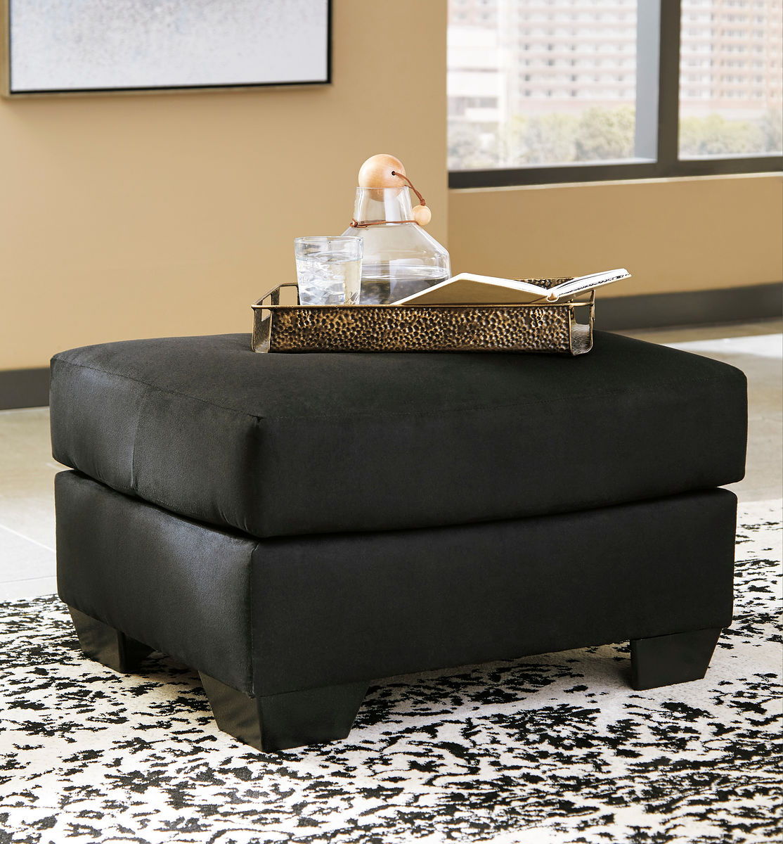 Black upholstered ottoman with padded top and square base, matching chair set