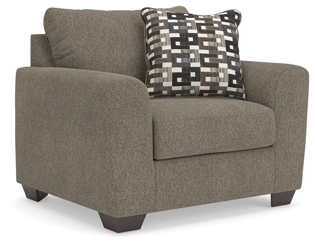Upholstered chair and a half in dark gray with geometric patterned throw pillow