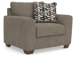 Upholstered chair and a half in dark gray with geometric patterned throw pillow