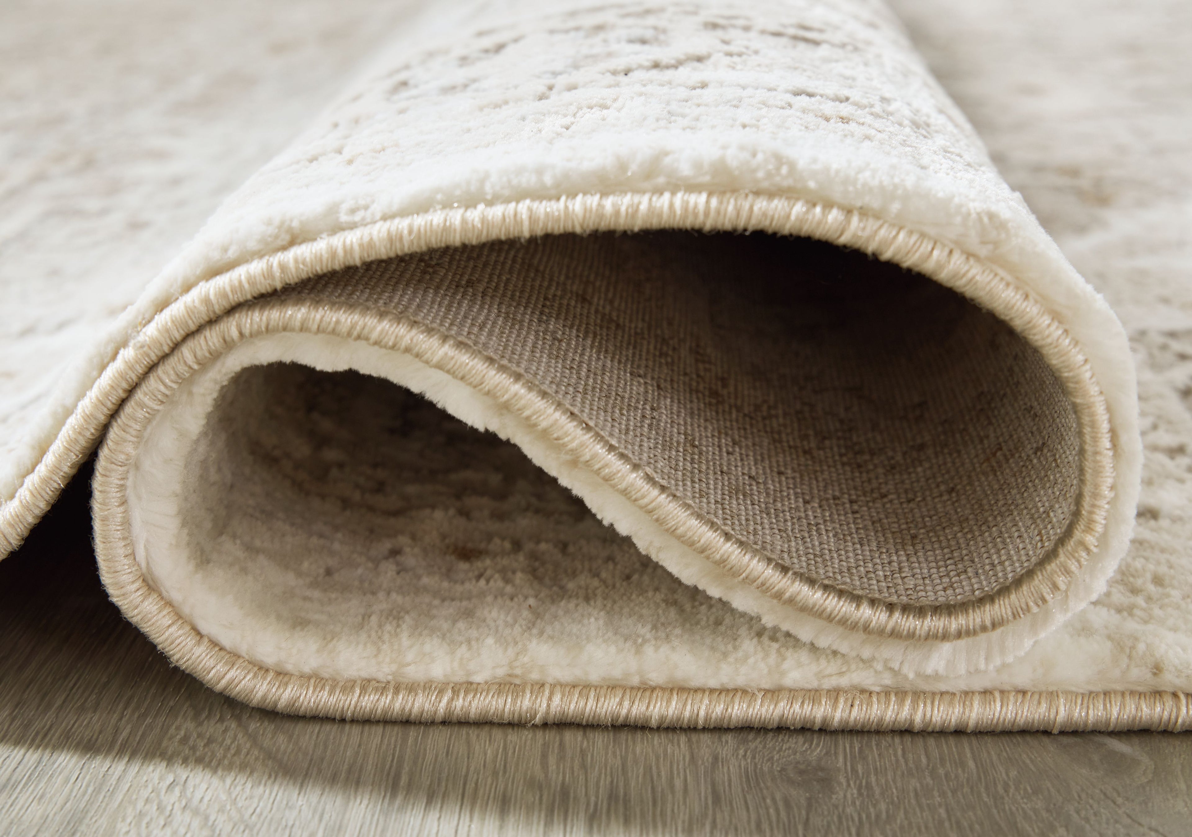 Beige rug edge with bound border, showing plush pile and folded underside