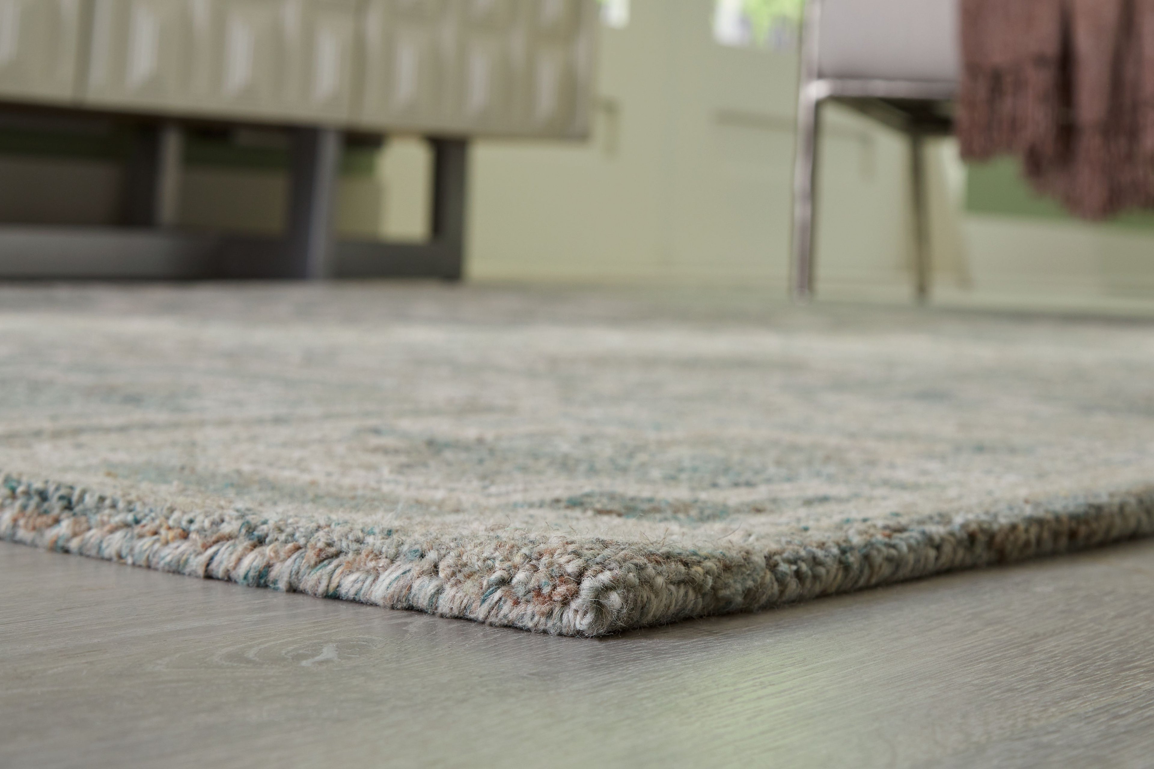 Green geometric area rug corner with short fringe and bound border