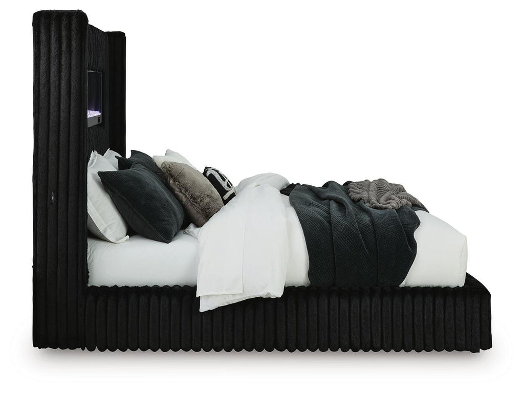 Black upholstered bed with ribbed frame, raised headboard, and stacked pillows