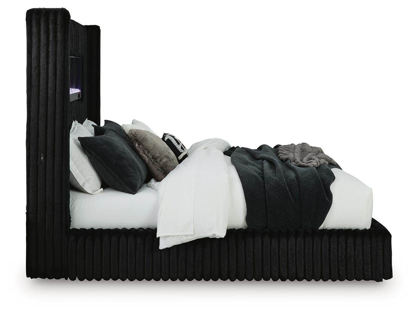 Black upholstered bed with ribbed frame, raised headboard, and stacked pillows