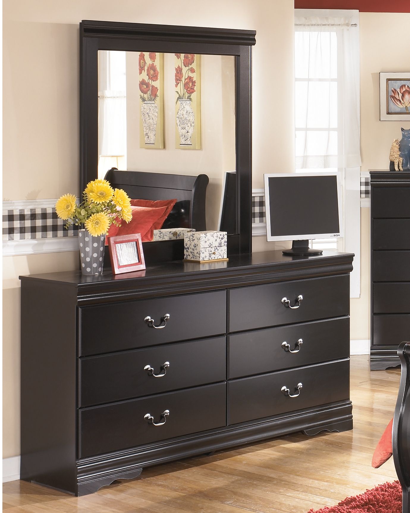 Black dresser with framed mirror and four drawers, curved metal handles