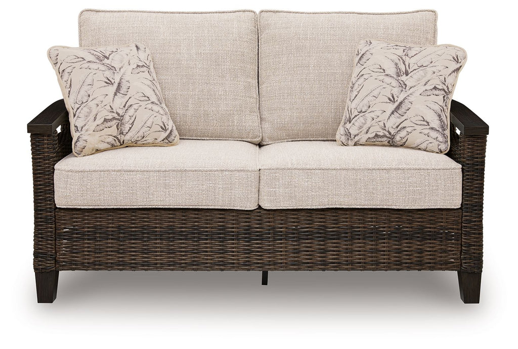 Dark brown wicker loveseat with two seat cushions and two patterned pillows