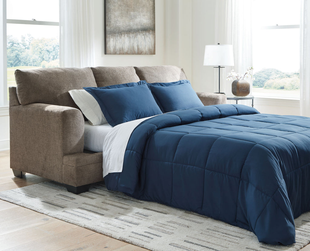 Sofa sleeper opened into a bed with blue comforter and cream accent bedding on taupe upholstery