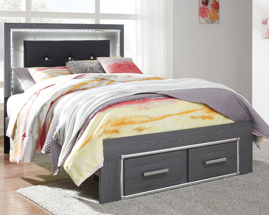 Gray bed with dark headboard and two storage drawers, colorful quilt and pillows