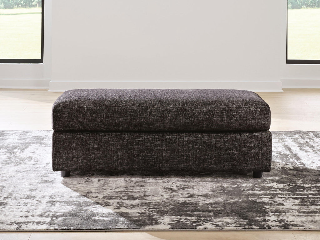 Oversized accent ottoman with dark upholstery, thick padded seat and short legs