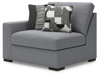 Gray upholstered corner chair with square seat, black legs, and patterned throw pillows