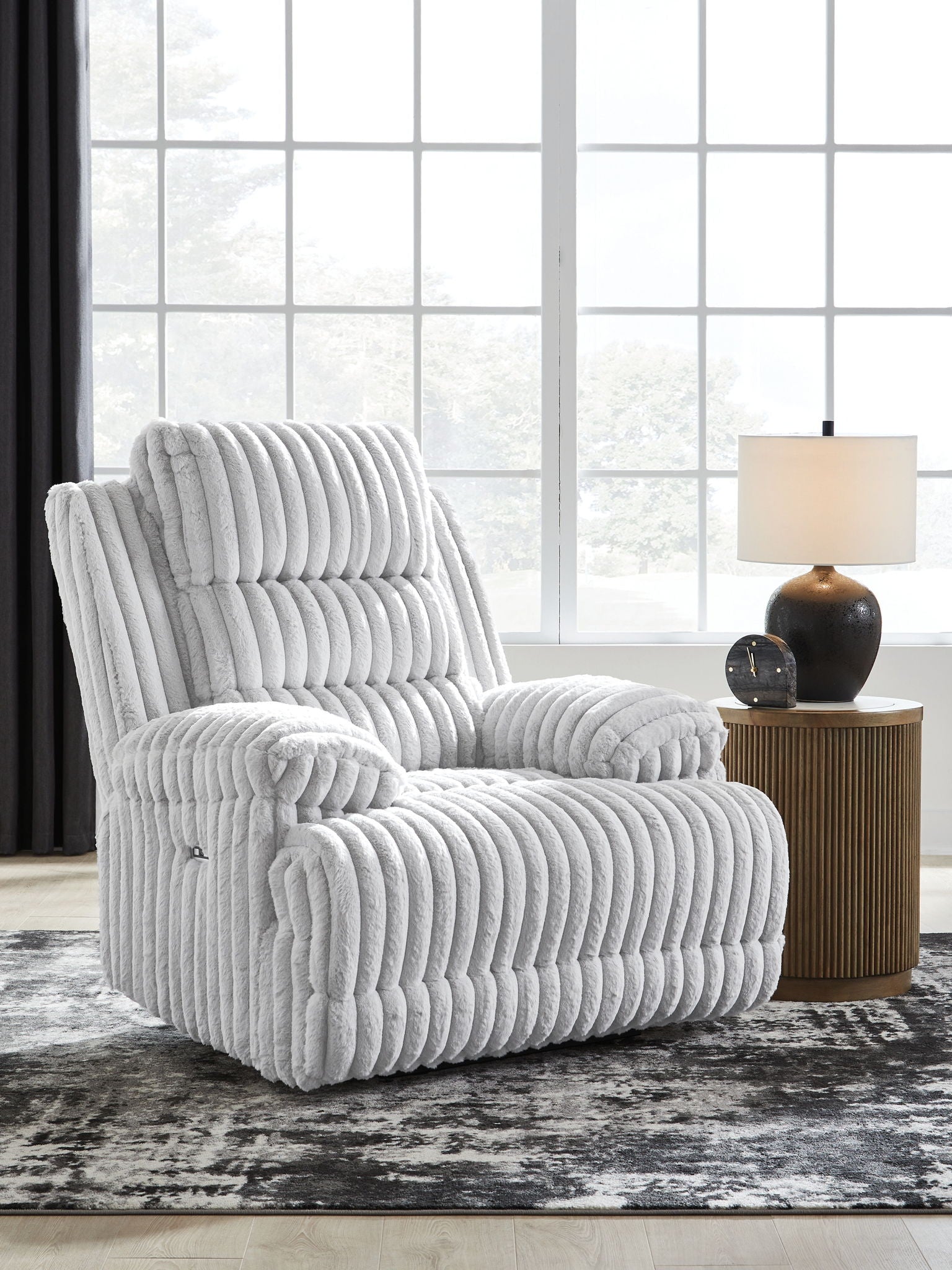 Light gray zero wall recliner chair with padded headrest and vertical channel tufting