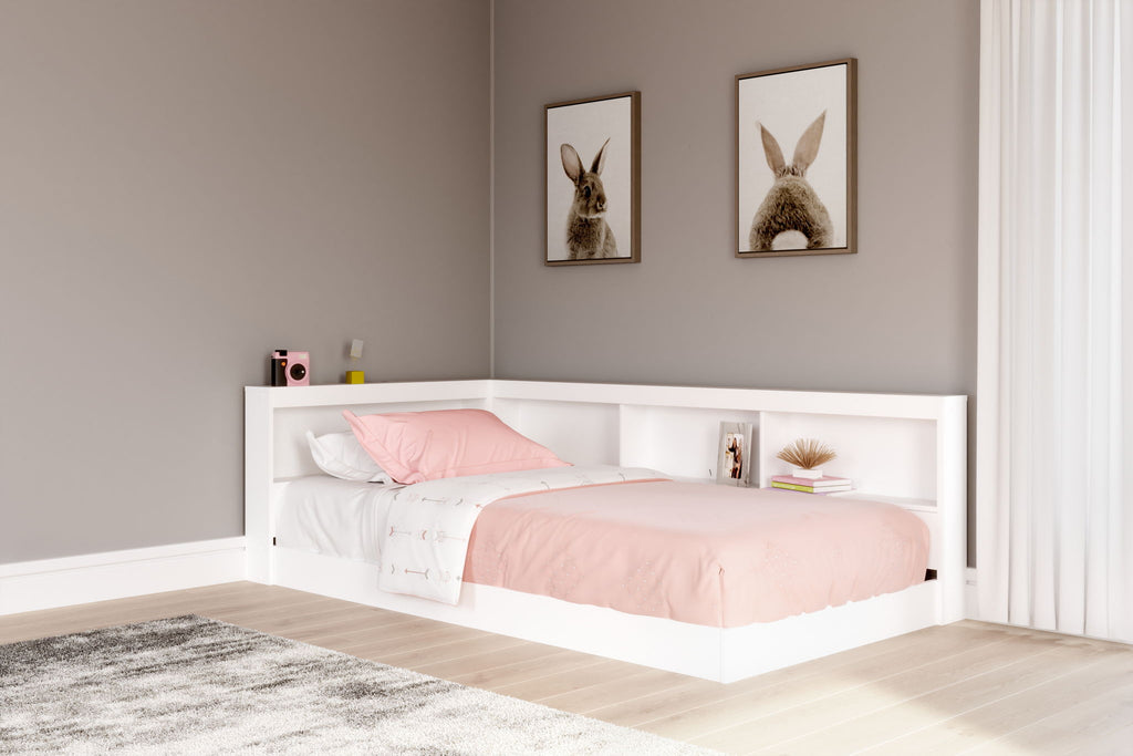 White storage bed with bookcase headboard and side cubbies, pink comforter and pillows