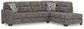 Dark gray L-shaped sectional sofa with right chaise, tufted back, and two striped throw pillows