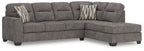 Dark gray L-shaped sectional sofa with right chaise, tufted back, and two striped throw pillows