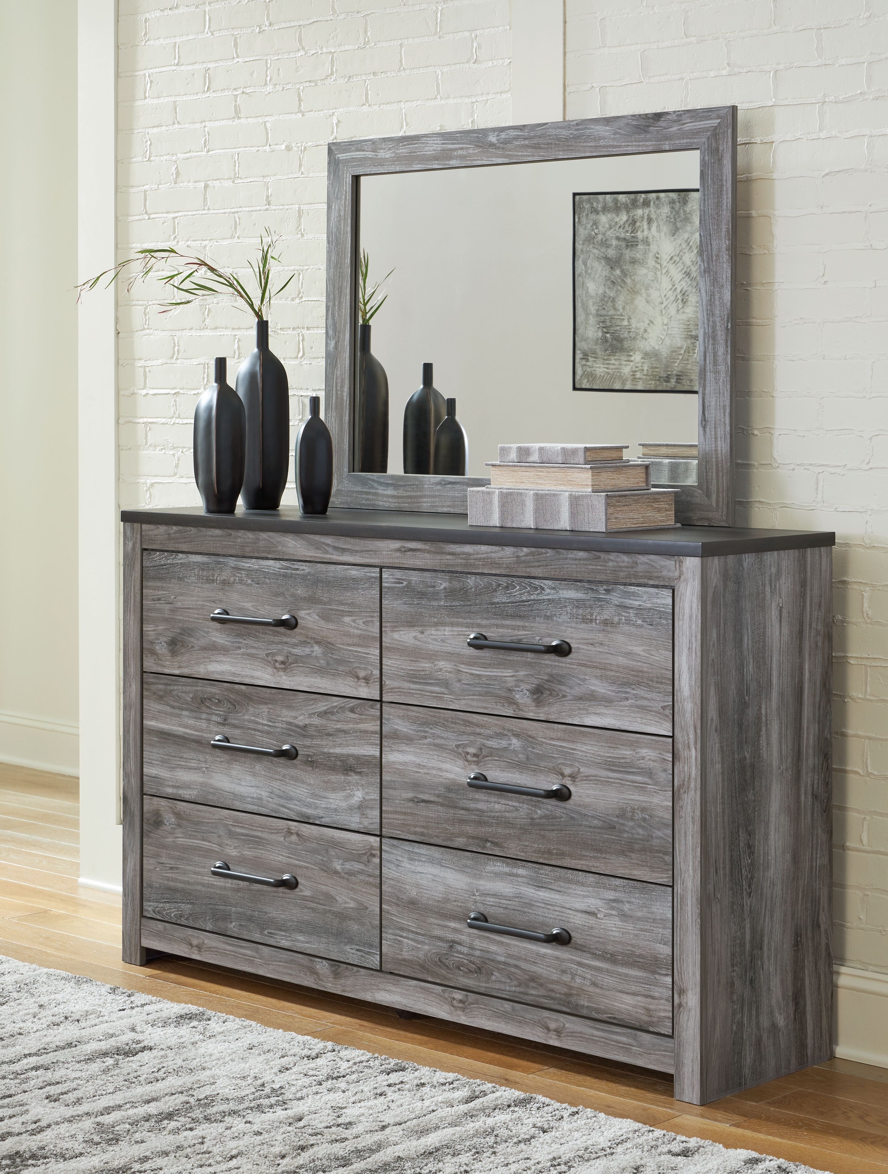 Dark gray dresser with wall mirror and four drawers, metal bar handles