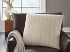 Beige pillow with vertical brown stripes, shown on a sofa