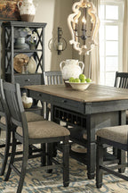 Dark gray counter height dining table with two slat-back bar stools and open shelf