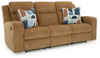 Light brown reclining sofa with two blue patterned throw pillows and padded arms