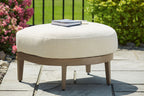 Beige cushioned round ottoman with dark brown wooden base