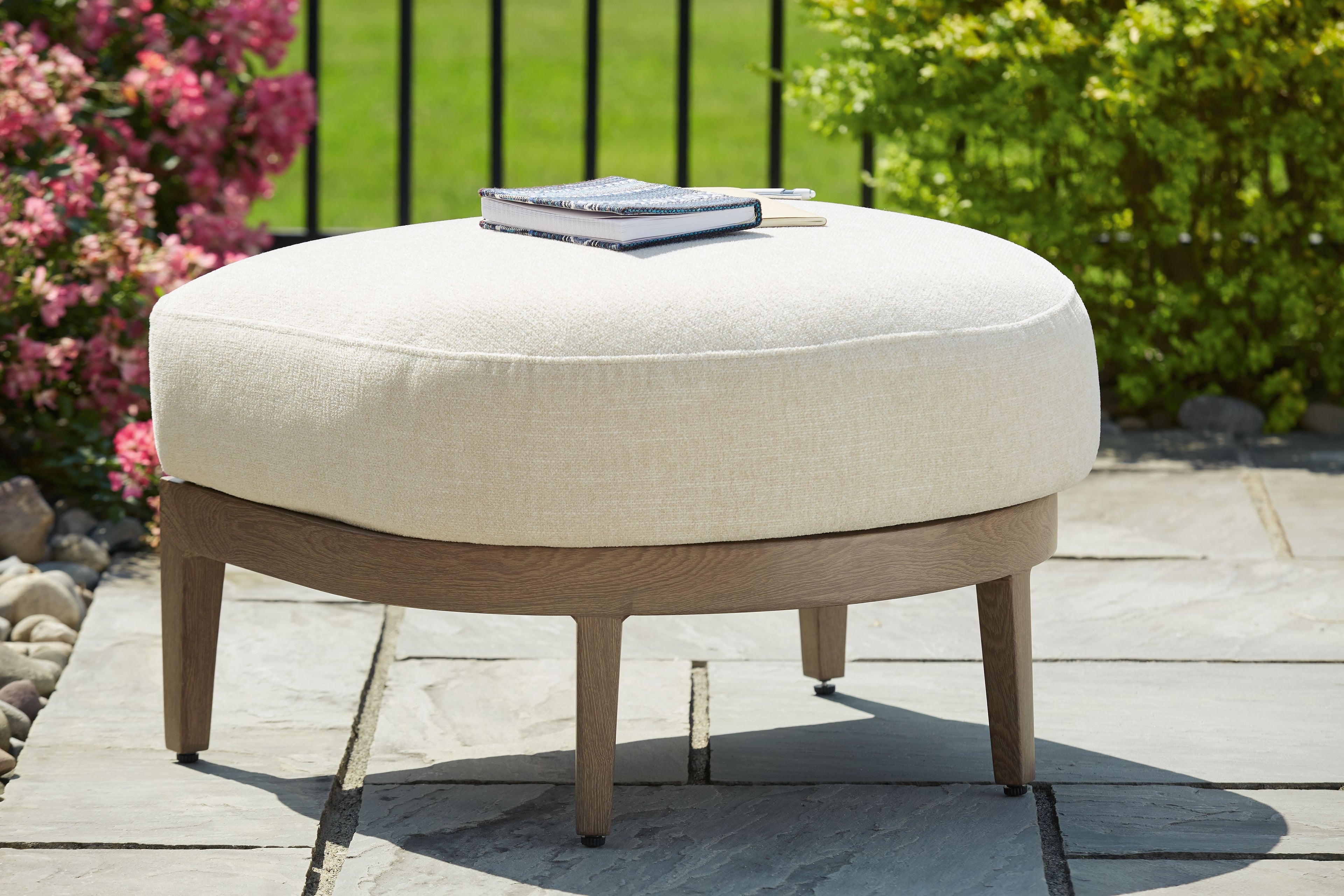 Beige cushioned round ottoman with dark brown wooden base