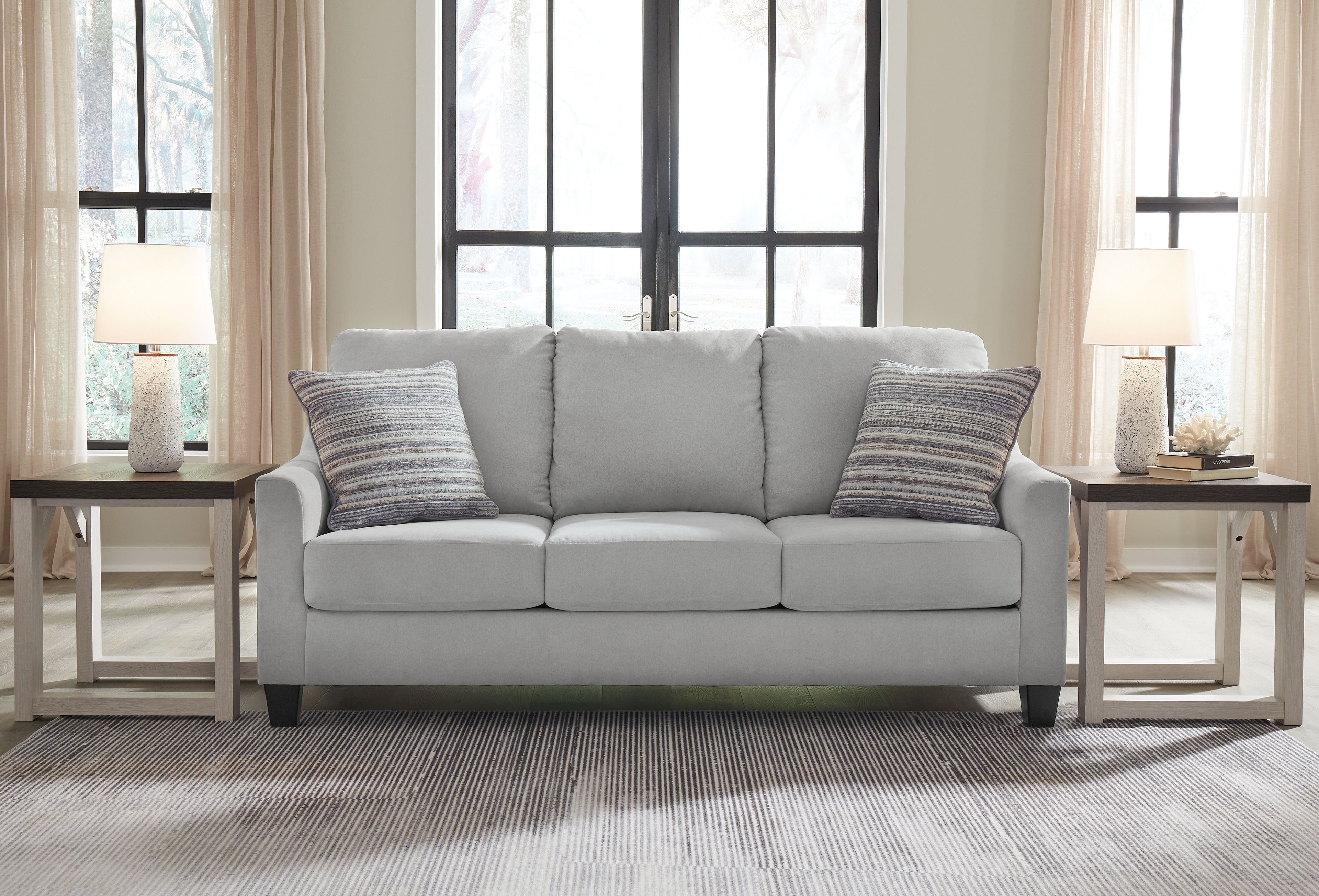 Gray fabric sofa with three seat cushions and two striped throw pillows