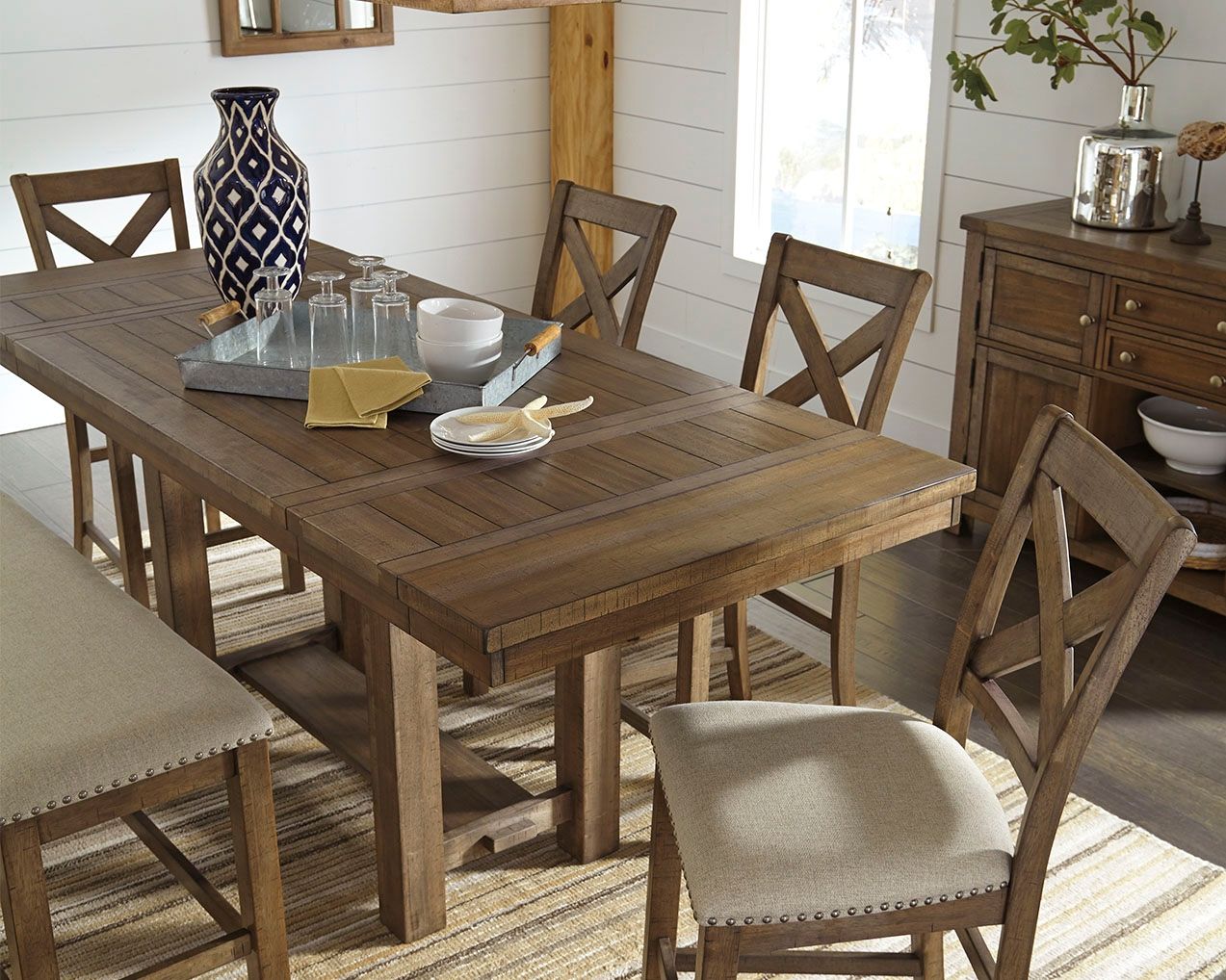 Rectangular dining table with grayish brown wood top and matching chairs in view