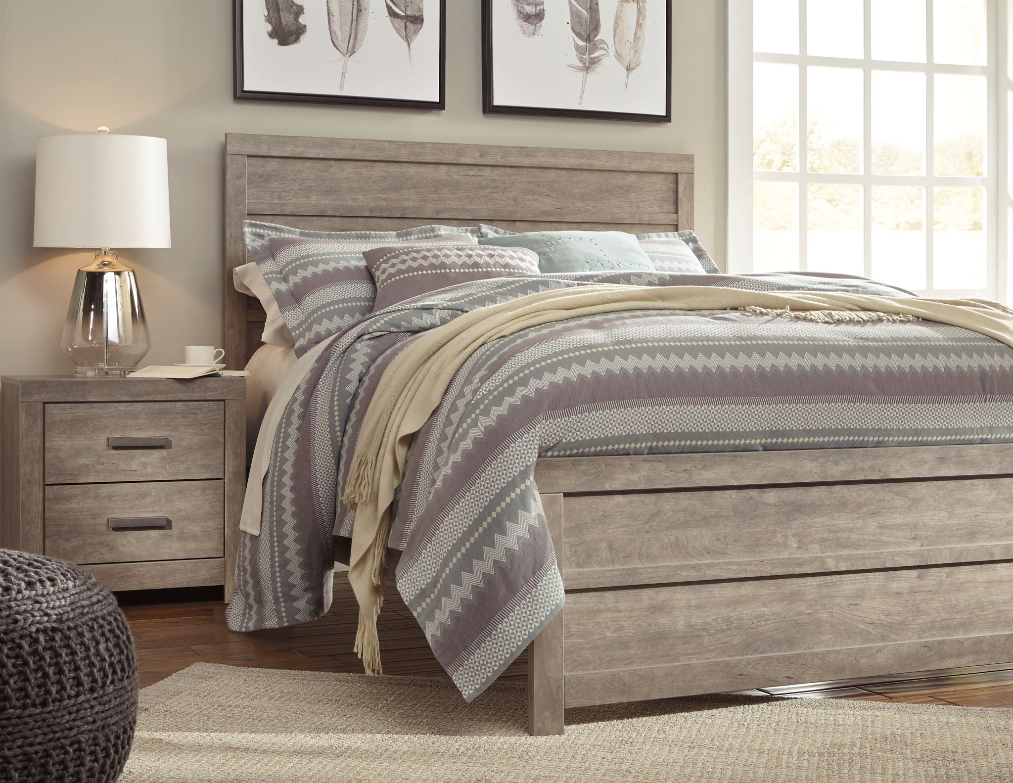 Gray panel bed frame with tall headboard, styled with striped and solid bedding