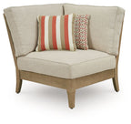 Beige fabric corner chair with two patterned throw pillows