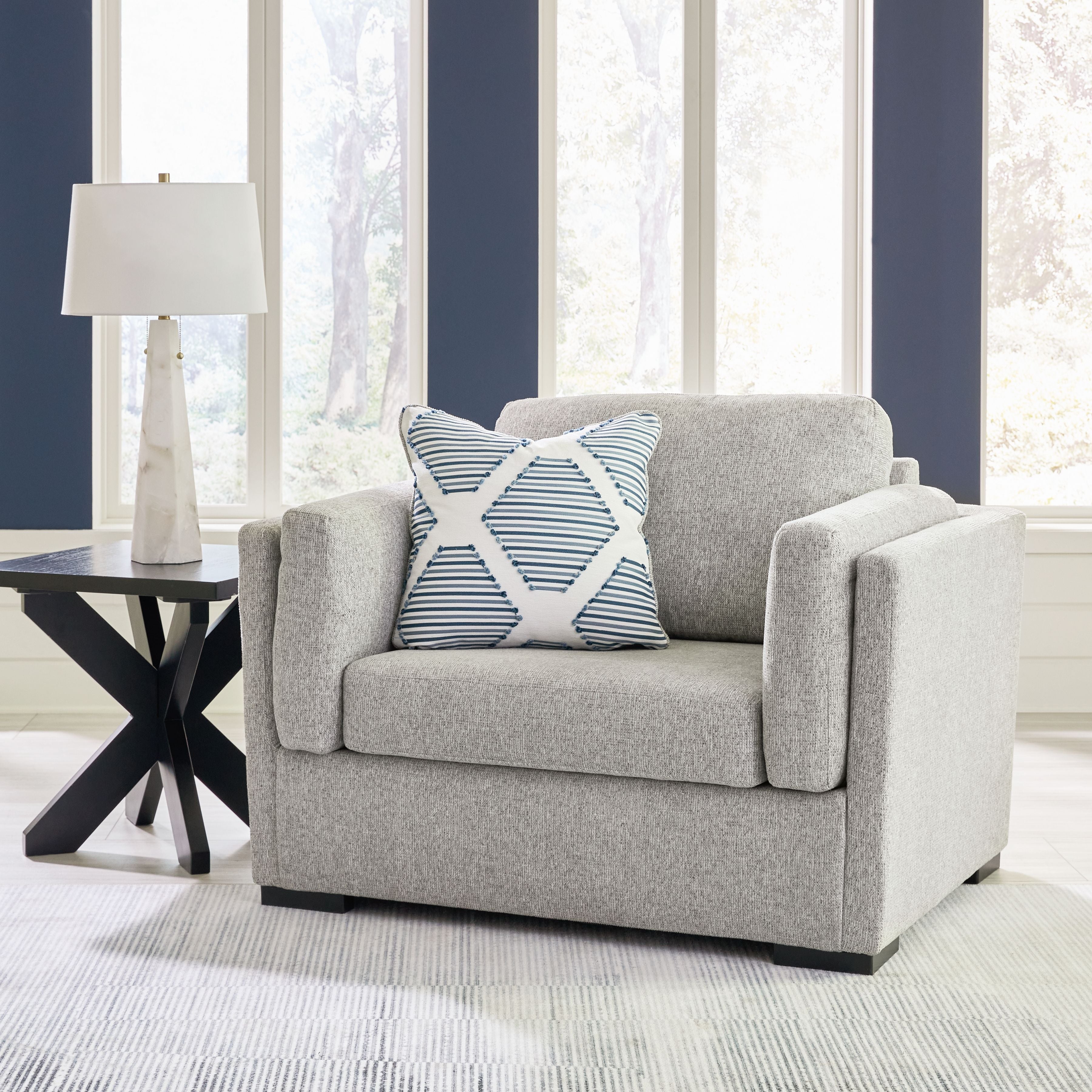Gray armchair with wide arms and a striped throw pillow