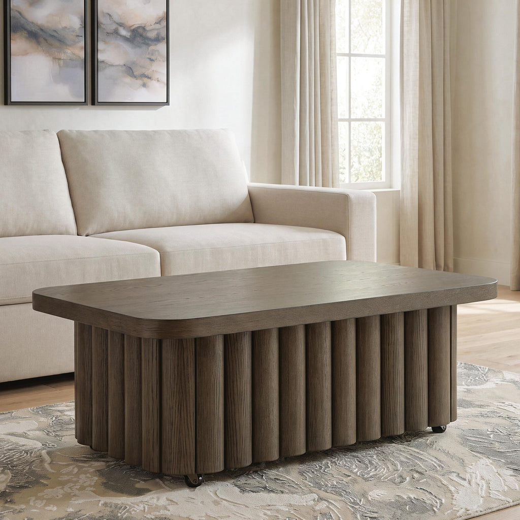 Dark brown oval coffee table with ribbed pedestal sides in a living room setting