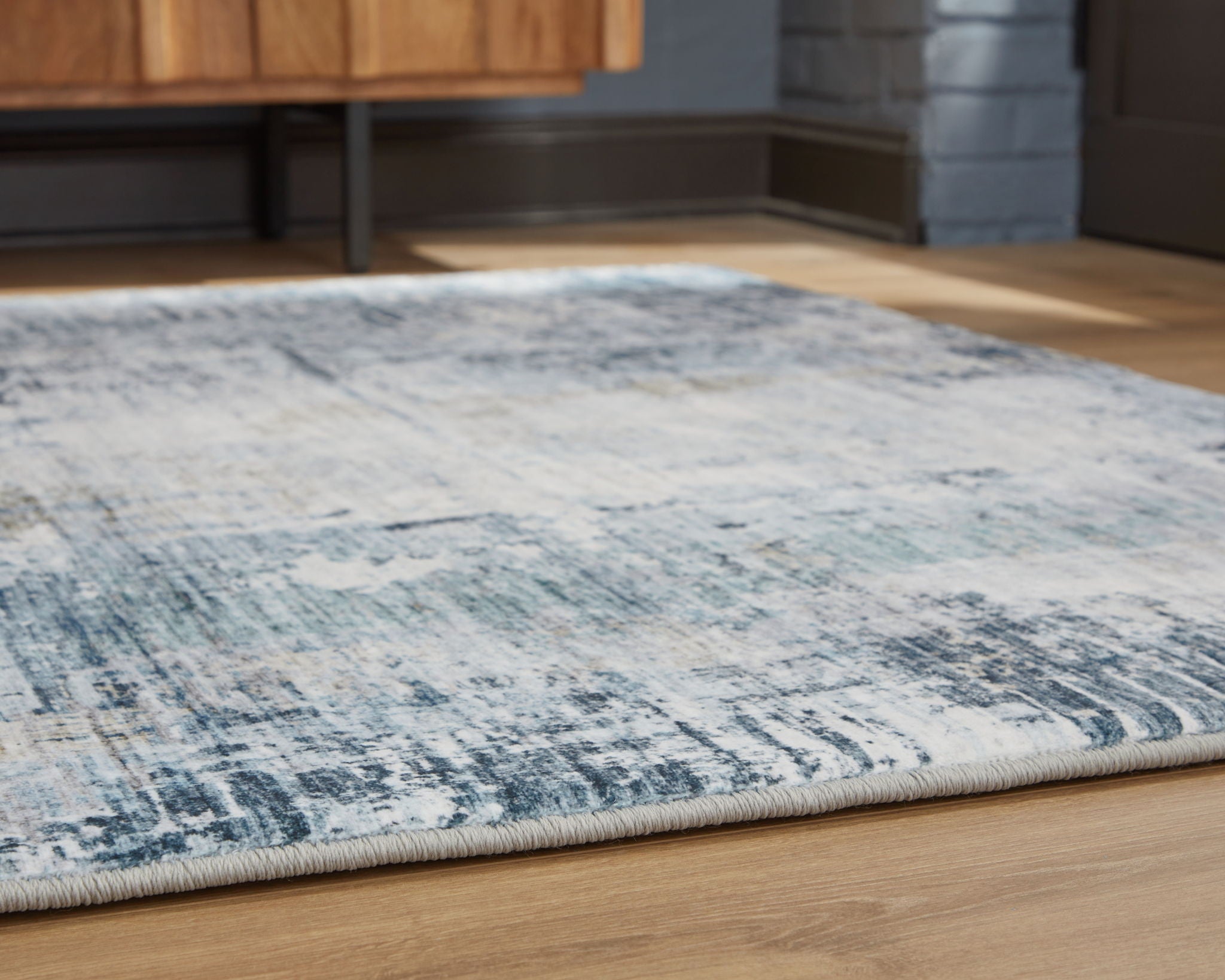 Blue and white abstract rug edge with tightly bound border and flat pile