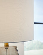 White drum lamp shade over gray glass base with gold stem