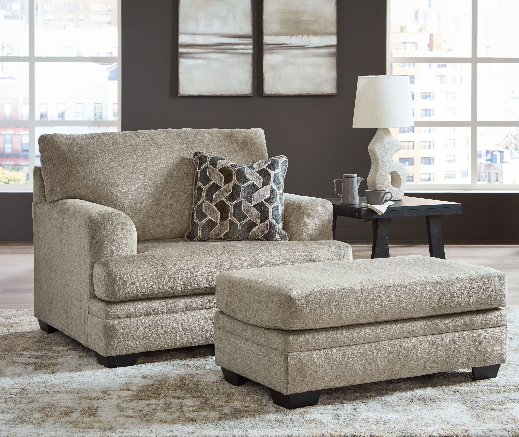 Taupe fabric loveseat with matching ottoman and geometric patterned throw pillows