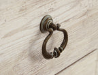 Antique-style metal ring pull on whitewashed cabinet drawer