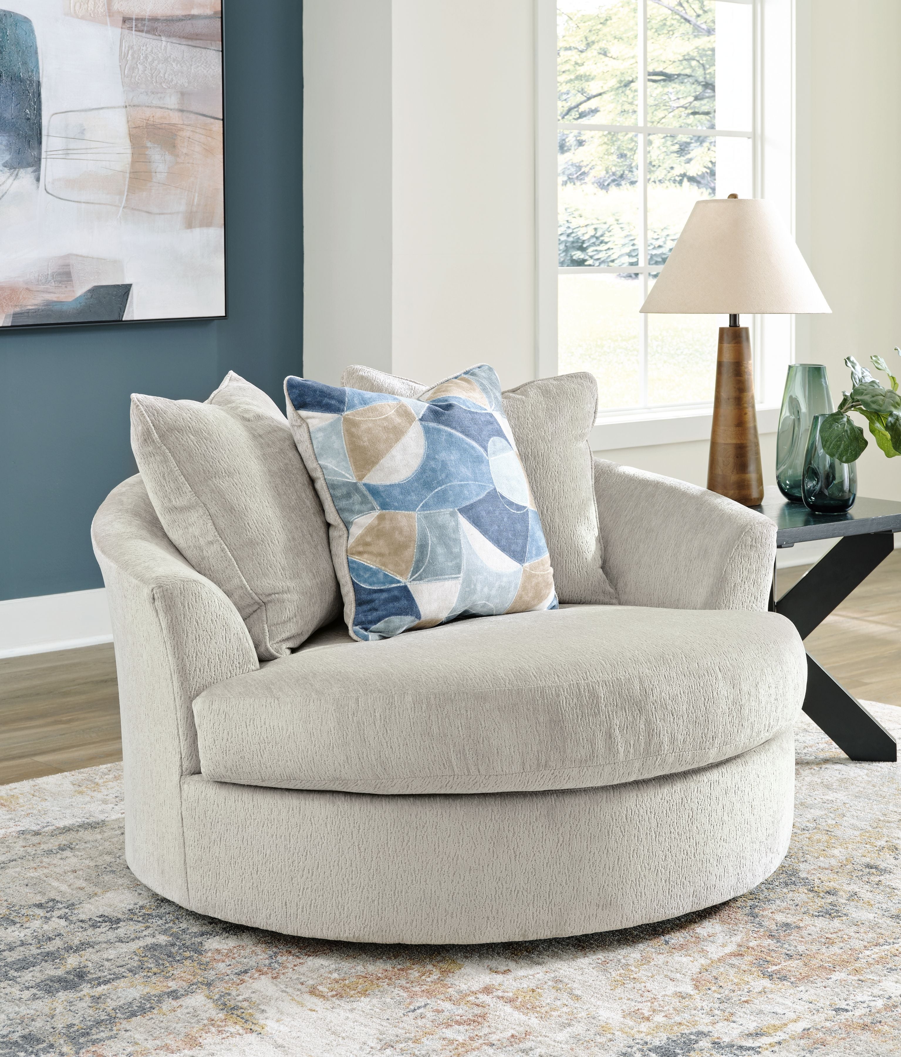 Beige oversized swivel accent chair with patterned throw pillow and rounded arms