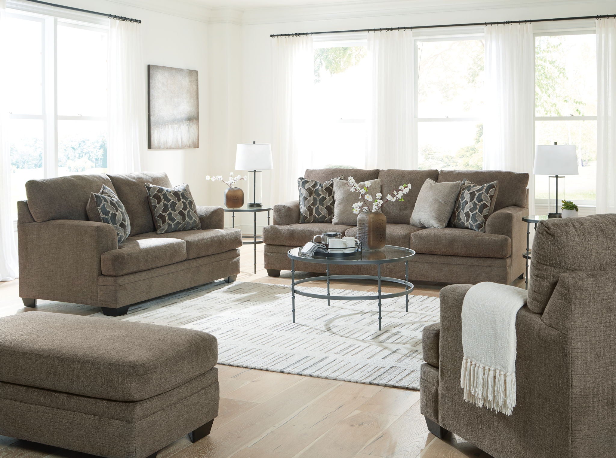 Taupe fabric living room sofa set with chaise, ottoman, and patterned accent pillows