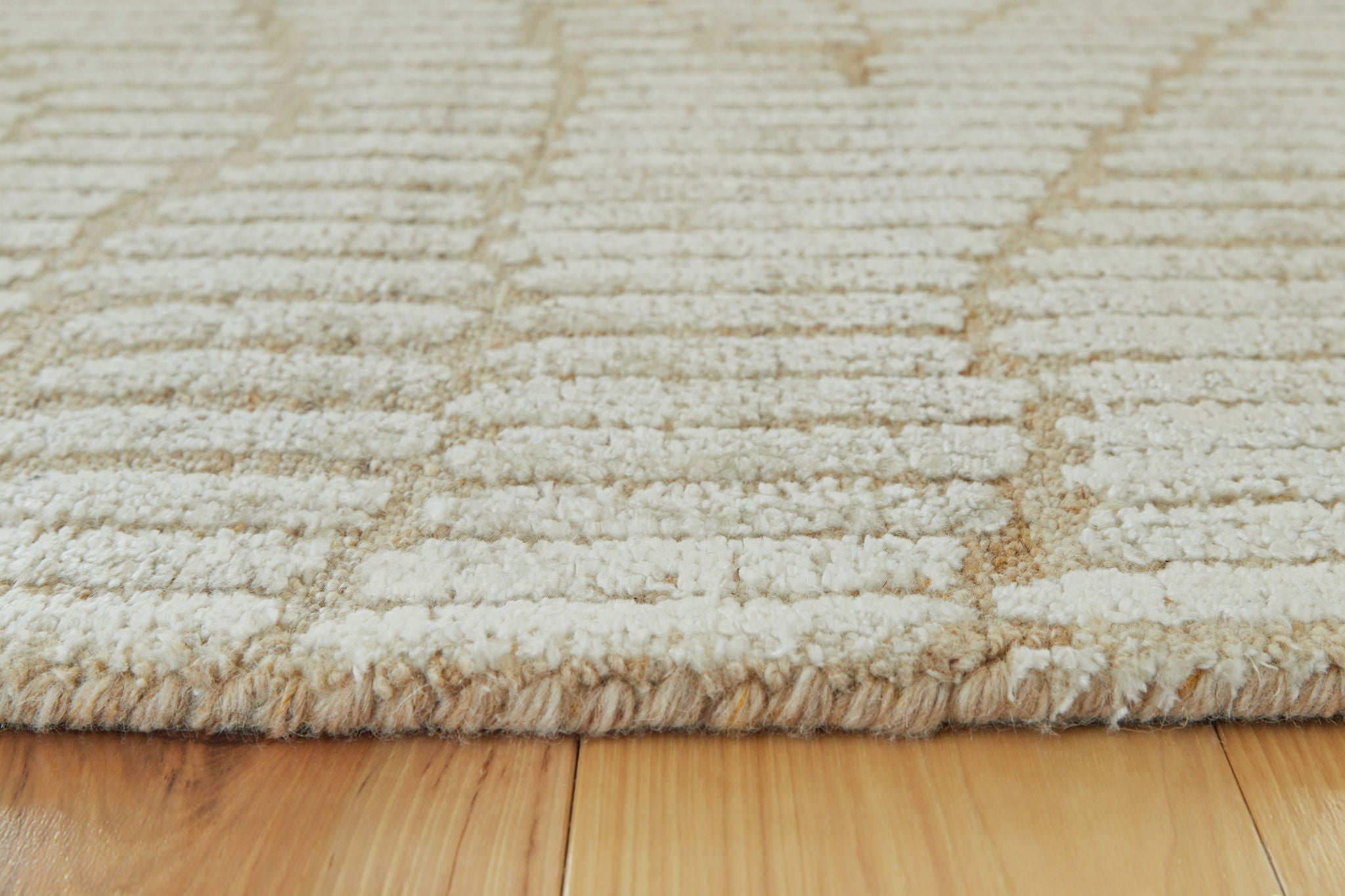 Beige rug close-up with textured loop weave and subtle wavy design