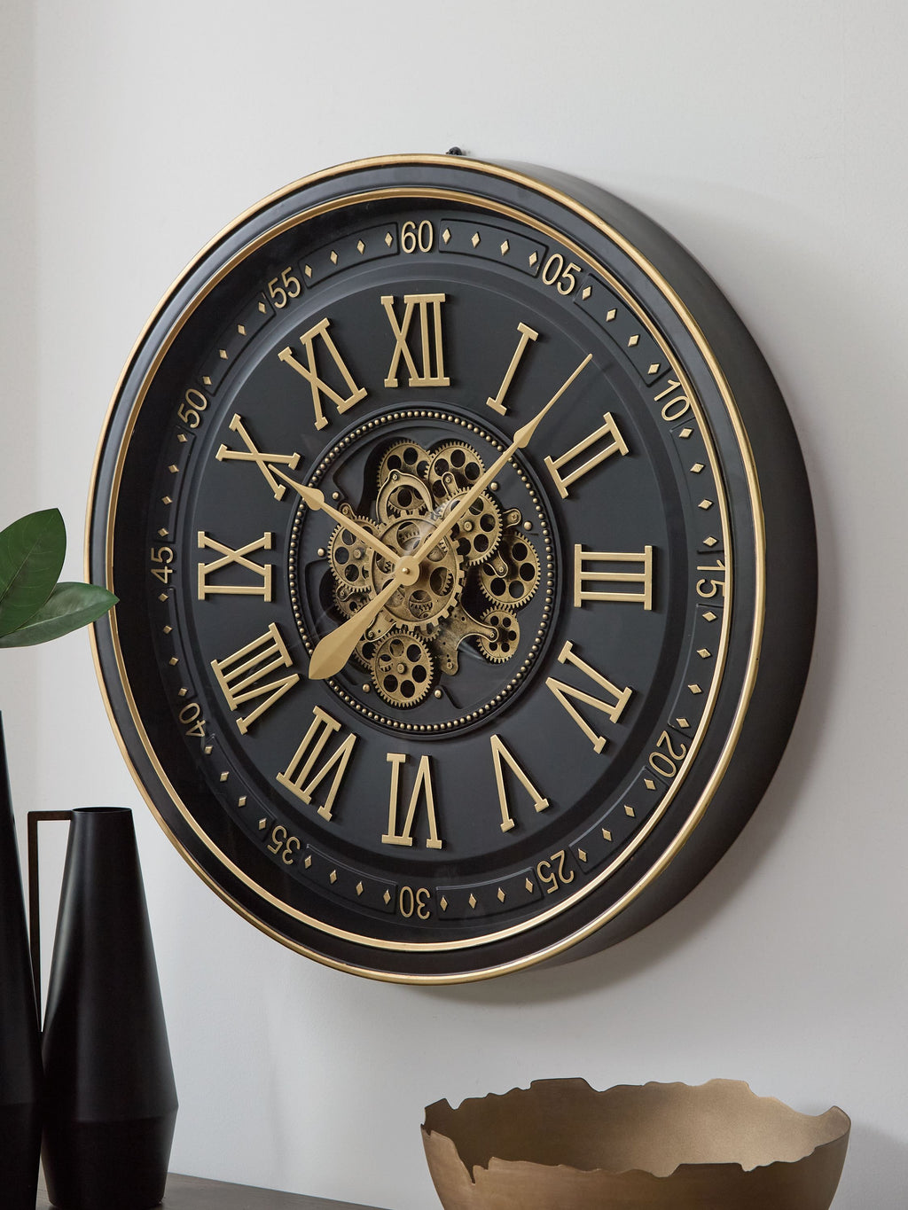 Black and gold wall clock with ornate gears, Roman numeral face, gold hands