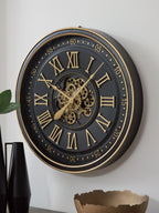 Black and gold wall clock with ornate gears, Roman numeral face, gold hands
