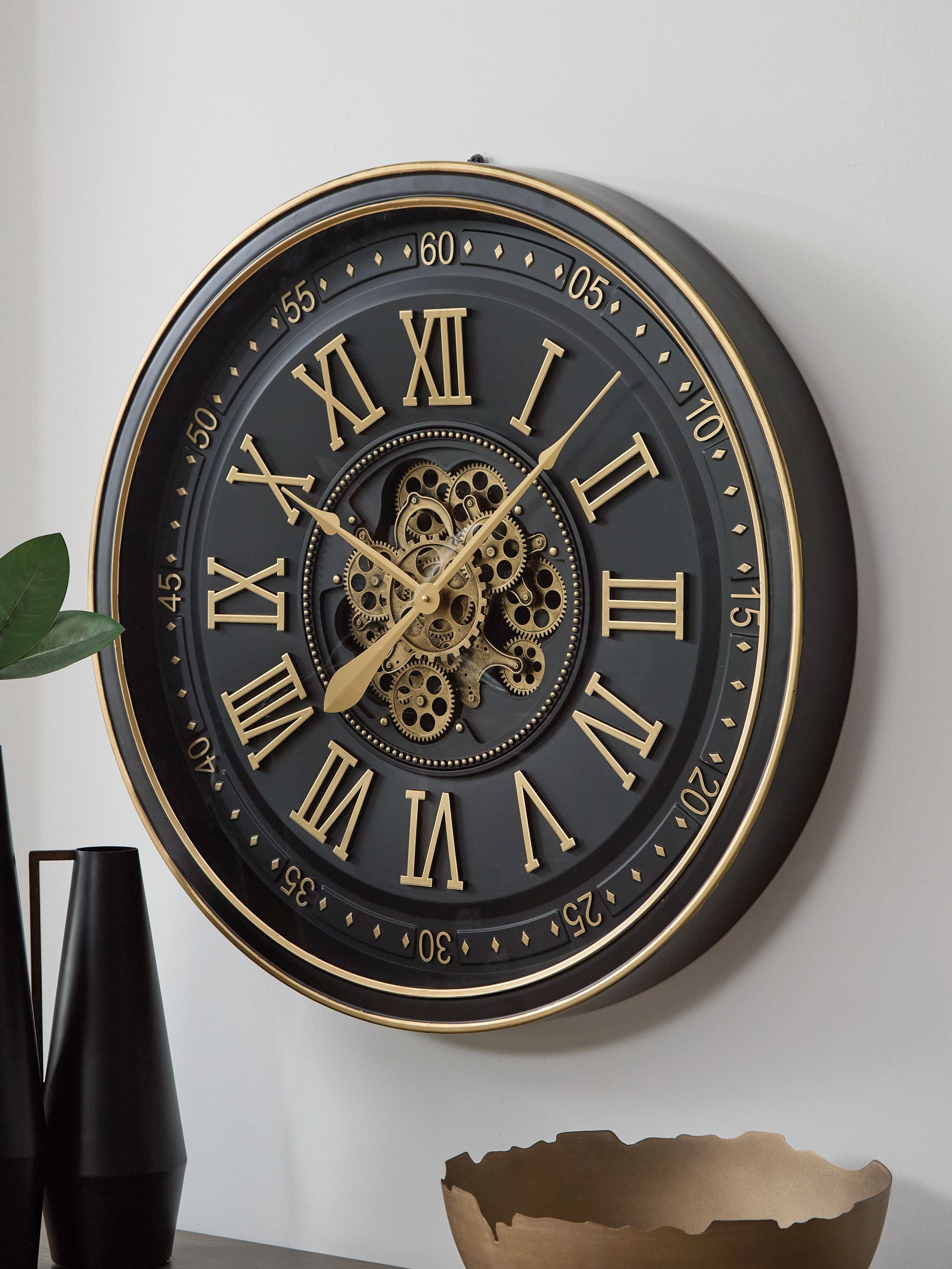 Black and gold wall clock with ornate gears, Roman numeral face, gold hands