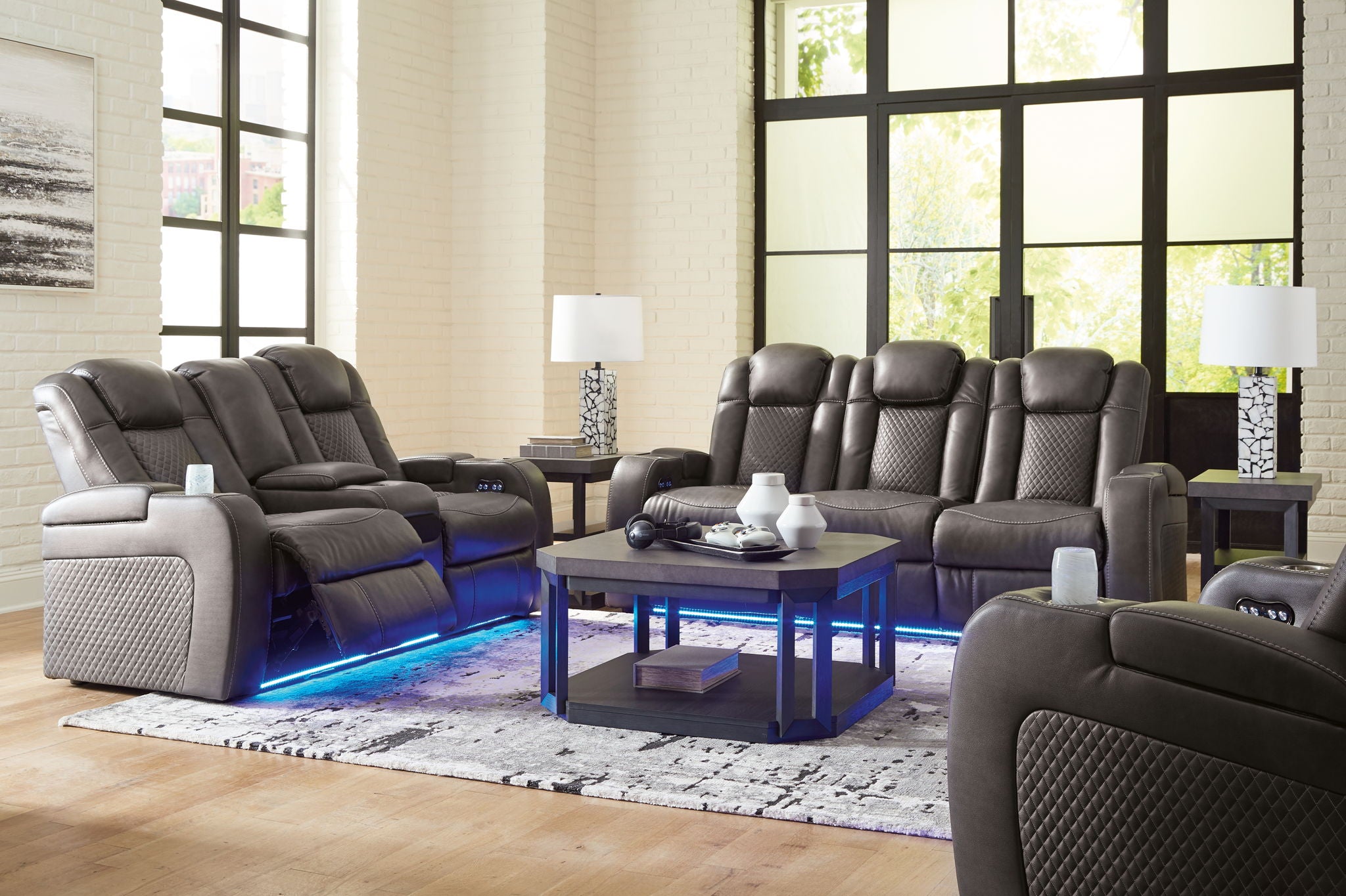 Dark gray reclining living room set with multiple recliners, tufted backs, and blue-lit base